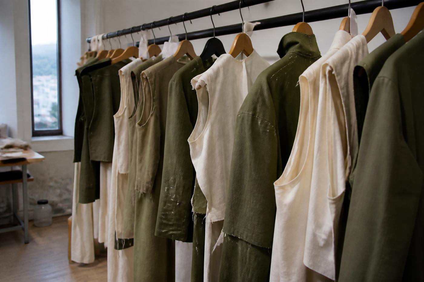Garments in progress hanging with visible basting thread